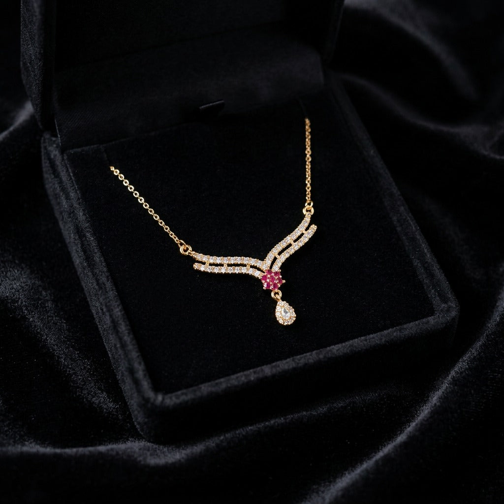 A delicate curve of shimmering crystals paired with a ruby-toned floral center, this necklace brings a graceful sparkle that feels soft, elegant, and effortlessly refined. The dangling crystal drop adds just the right touch of movement for a timeless feminine finish.