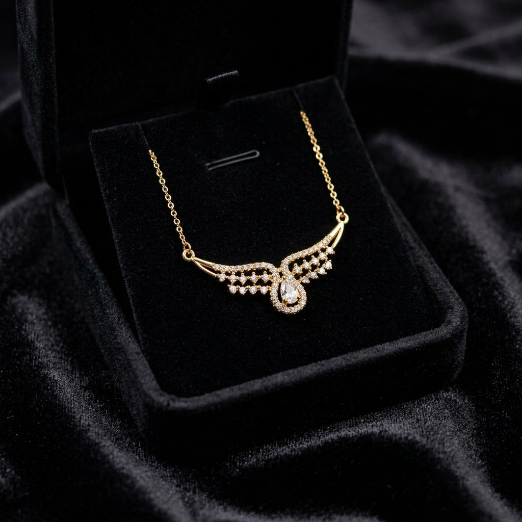 A graceful curve of shimmering crystals flowing into a radiant teardrop centerpiece, this necklace captures an elegant sparkle that feels delicate yet striking. The wing-like silhouette and soft crystal shine create a timeless look perfect for both festive styling and everyday elegance.