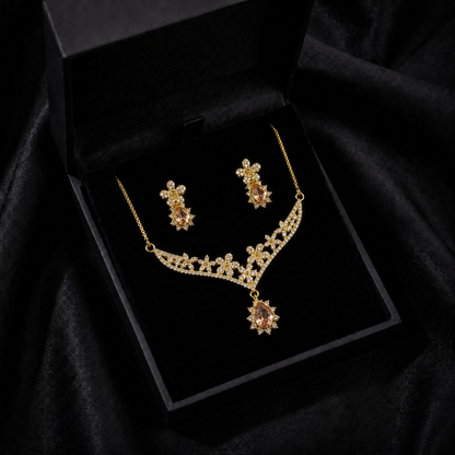 A delicate bloom of crystal flowers and warm champagne-toned stones, this set captures the elegance of a garden kissed by golden light. The floral vine silhouette paired with soft teardrop accents creates a graceful sparkle that feels romantic, refined, and timeless.