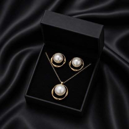 Capture the timeless beauty of the ocean’s treasures with the Gilded Ripple Set. This exquisite necklace and earring duo features a luminous, jumbo artificial pearl nestled within a flowing golden orbit, creating a look that is both bold and gracefully sophisticated.