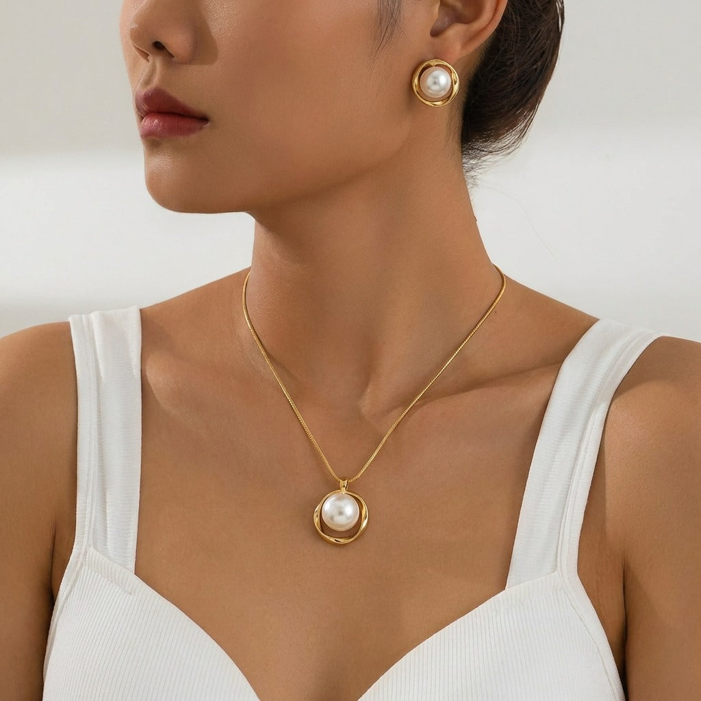 Capture the timeless beauty of the ocean’s treasures with the Gilded Ripple Set. This exquisite necklace and earring duo features a luminous, jumbo artificial pearl nestled within a flowing golden orbit, creating a look that is both bold and gracefully sophisticated.