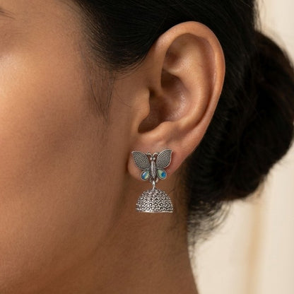 A delicate blend of fluttering grace and traditional charm, this piece captures the beauty of butterfly-inspired detailing with a soft, elegant touch. The textured dome paired with subtle blue accents and gentle drops creates a movement that feels light, dreamy, and effortlessly refined.