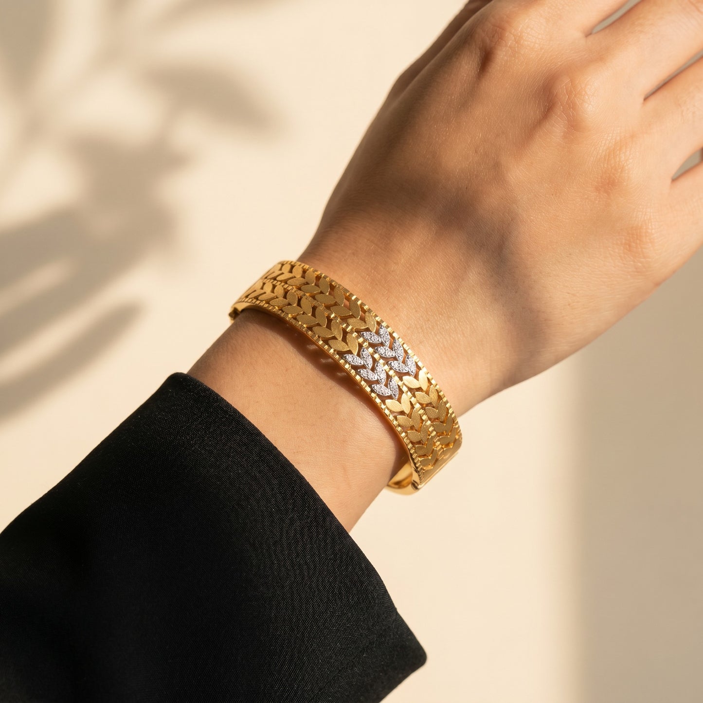 A timeless blend of heritage elegance and refined artistry, this bangle captures the beauty of woven leaf motifs in a rich golden silhouette. The alternating polished details and sparkling accents create a regal look that feels both traditional and luxurious.