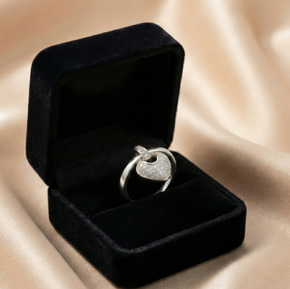 A romantic statement ring defined by a delicate hanging heart silhouette, softly paved with shimmering zircon stones. The Velmora Heart Ring is designed to capture love in motion graceful, expressive, and full of feeling. Its suspended heart detail adds gentle movement, making the design feel alive, emotional, and irresistibly charming.