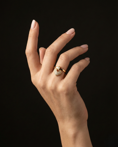 A romantic statement ring defined by a delicate hanging heart silhouette, softly paved with shimmering zircon stones. The Velmora Heart Ring is designed to capture love in motion graceful, expressive, and full of feeling. Its suspended heart detail adds gentle movement, making the design feel alive, emotional, and irresistibly charming.