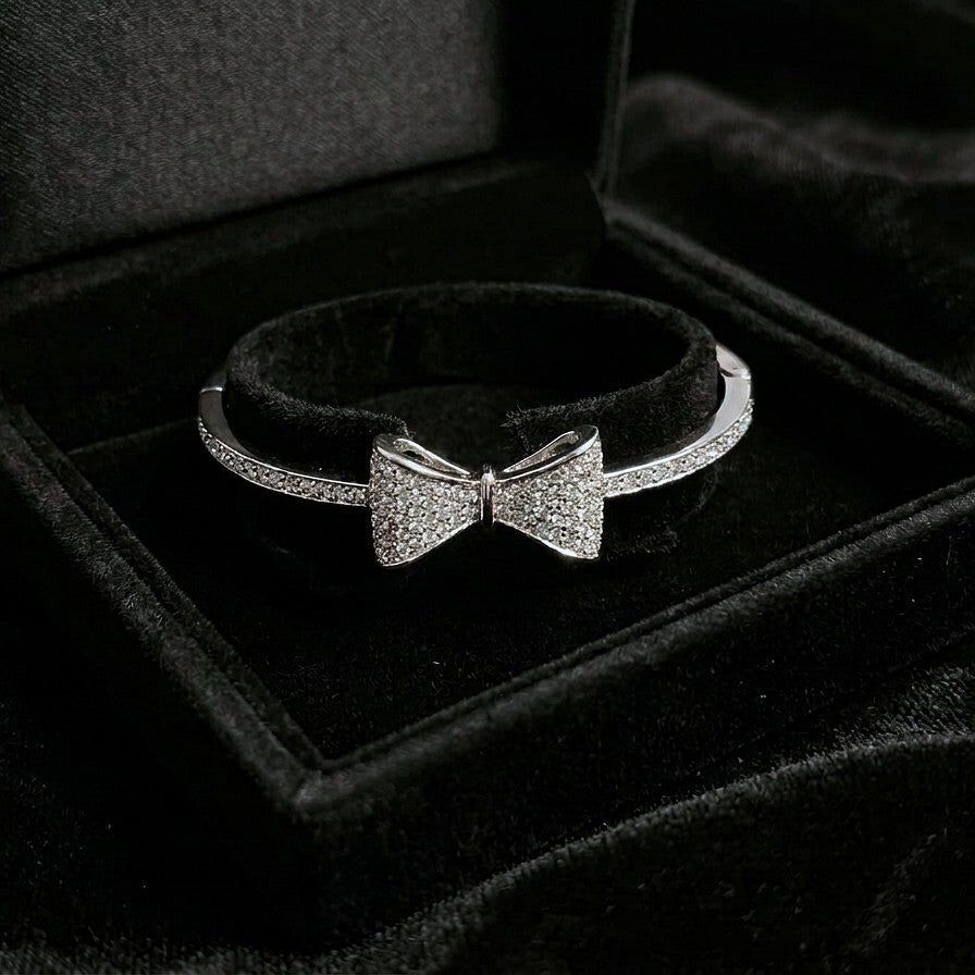A delicate symbol of elegance and charm, this bow-inspired bracelet captures a soft sparkle that feels both graceful and modern. The sleek curve paired with shimmering stone detailing creates a refined look that effortlessly elevates everyday style.